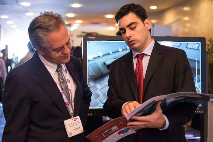 Dois executivos conversando e folheando uma revista em evento corporativo